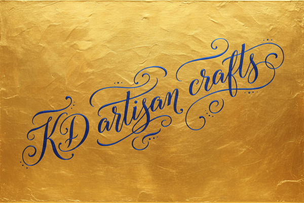Canvas with gold background and KD artisan crafts written in script in blue at a diagonal